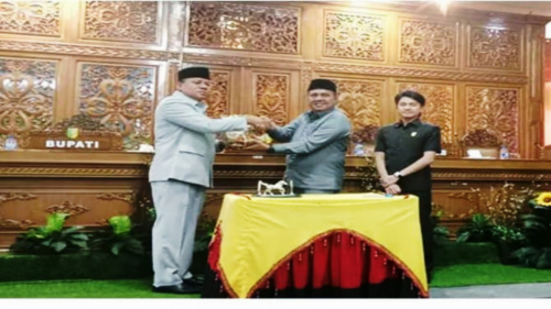 Ketua DPRD Kuansing H Juprizal SE MSi menyerahkan buku petanda di sahkannya APBD 2025 pada Bupati Kuansing H Suhardiman Amby pada agenda rapat paripurna.